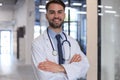 Handsome friendly young doctor on hospital corridor looking at camera, smiling Royalty Free Stock Photo