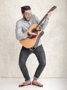 Handsome funny man playing an acoustic guitar against grunge wall Royalty Free Stock Photo