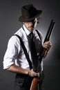 Handsome gangster posing with shotgun and hat