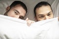 A Handsome gay men couple on bed together under the cover Royalty Free Stock Photo