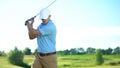 Handsome golfer ready to hit ball, taking swing position, club-and-ball sport