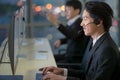 Handsome good looking Asian male workers wearing headphone headset and working with happy face in front of computer screen at call Royalty Free Stock Photo