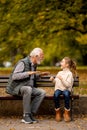 Grandfather playing red hands slapping game with his granddaughter in park on autumn day Royalty Free Stock Photo