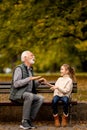 Grandfather playing red hands slapping game with his granddaughter in park on autumn day Royalty Free Stock Photo