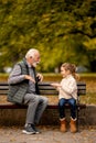 Grandfather playing red hands slapping game with his granddaughter in park on autumn day Royalty Free Stock Photo