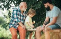 Handsome grandpa and grandson are playing chess while spending time together outdoor. Boy with father and grandfather Royalty Free Stock Photo