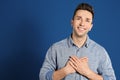 Handsome grateful man with hands on chest against background