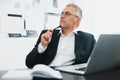 Handsome gray-haired businessman in elegant suit sits in office holding pen in hand thinking on new idea while working Royalty Free Stock Photo