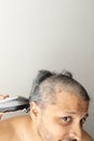 Handsome gray-haired man is cutting hair himself