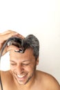 Handsome gray-haired man is cutting hair himself