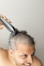 Handsome gray-haired man is cutting hair himself