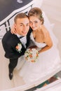 Handsome groom and beautiful bride embracing looking up. Top view Royalty Free Stock Photo