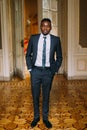 Handsome groom in black suit posing. Luxurious hotel room background Royalty Free Stock Photo