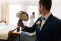 Handsome groom with bouquet posing at beautiful bride background in hotel room