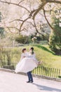 Handsome groom carrying beautiful laughing bride in his arms at spring park Royalty Free Stock Photo