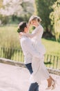 Handsome groom carrying beautiful laughing bride in his arms at spring park Royalty Free Stock Photo