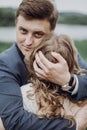 Handsome groom embracing beautiful bride and looking into the camera, happy newlyweds portrait, couple hugging outdoors Royalty Free Stock Photo