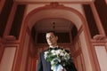 Handsome Groom holding stylish bouquet in the morning in the luxury room. sensual man portrait in suit with flowers in luxury