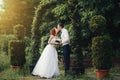 Handsome groom holds the bride`s hand near green flower archway Royalty Free Stock Photo