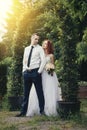 Handsome groom holds the bride`s hand near green flower archway Royalty Free Stock Photo