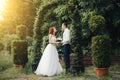 Handsome groom holds the bride& x27;s hand near green flower archway Royalty Free Stock Photo