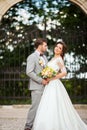 Handsome groom hugging beautiful bride with bouquet in romantic european park Royalty Free Stock Photo