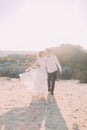 Handsome groom in white shirt and bride wearing bridal dress walking kissing against the backdrop of city Royalty Free Stock Photo