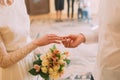 Handsome groom in white shirt putting wedding ring on stylish bride at registry, close-up