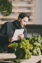 Handsome grower using his tablet while growing plants