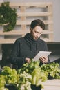 Handsome grower using his tablet while growing plants