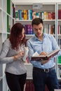 Handsome guy and beautiful redhead girl studying in the library Royalty Free Stock Photo