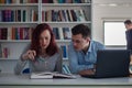 Handsome guy and beautiful redhead girl studying in the library Royalty Free Stock Photo