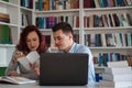 Handsome guy and beautiful redhead girl studying in the library Royalty Free Stock Photo