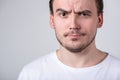 Handsome guy with bristles in a white T-shirt makes funny grimaces on his face