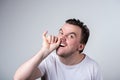 Handsome guy with bristles in a white t-shirt picks his finger in his nose