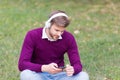 Handsome guy on green grass change song on mobile phone mp3 player and listens to music in earphones, digital age Royalty Free Stock Photo