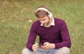 handsome guy on green grass change song on mobile phone mp3 player and listens to music in earphones, digital age Royalty Free Stock Photo