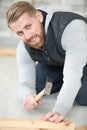 Handsome guy hammering nail into wood plank