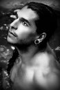 A handsome guy with long hair and piercings on waterfalls in a rain forest. Black and white photo Royalty Free Stock Photo