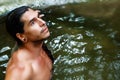 A handsome guy with long hair and piercings on waterfalls in a rain forest. Black and white photo Royalty Free Stock Photo