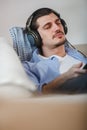 Handsome guy lying on sofa with tablet and headphones Royalty Free Stock Photo