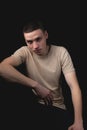 Handsome guy posing in studio on black background. Studio portrait with one light source