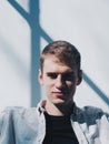 Handsome guy smiling to the camera covered with shadow at sunny day. Vertical photo