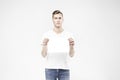 Handsome guy standing with blank sheet in hand, isolated on white background, wearing jeans and t-shirt. available space for layou Royalty Free Stock Photo