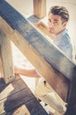 Handsome guy with trendy hairstyle going down wooden stairs while looking. Royalty Free Stock Photo