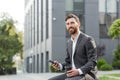 Handsome happy bearded businessman sitting on bench with cup coffee use mobile phone browse smartphone in hands reads good news Royalty Free Stock Photo