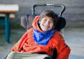 Handsome, happy biracial eight year old boy smiling in wheelchair outdoors