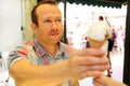 Handsome happy man sells ice cream in shop. Kind female seller in candy store gives ice cream to boy.