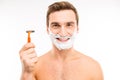 Handsome happy man with shaving foam on his face holding razor Royalty Free Stock Photo