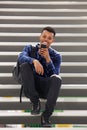 Handsome happy man sitting on steps using smart phone Royalty Free Stock Photo